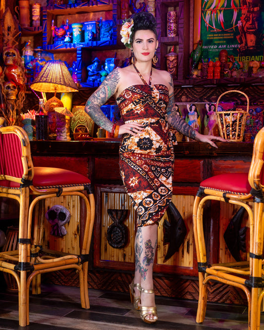 Woman in a patterned dress standing in a bar with colorful decor