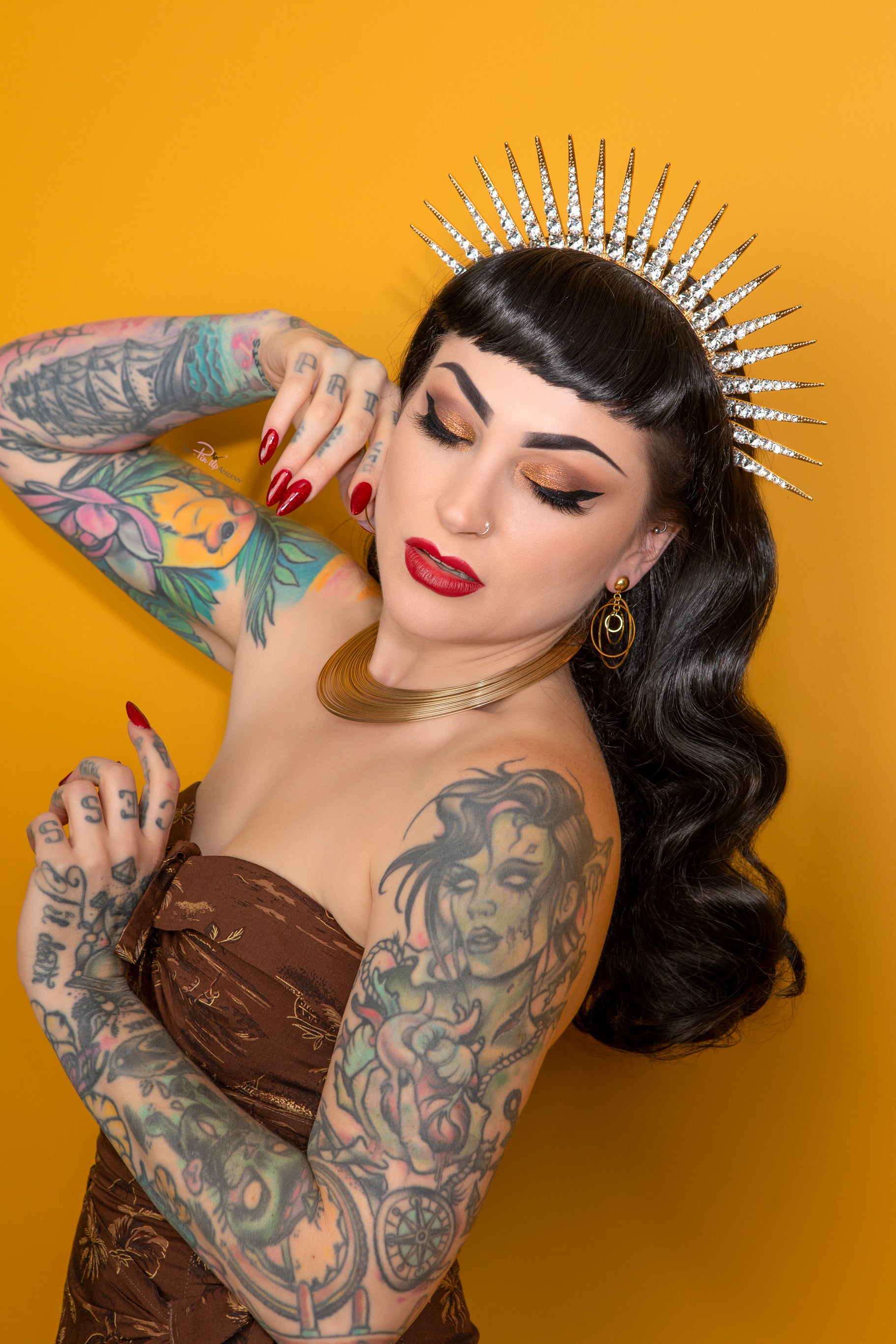 Woman with tattoos and a decorative headpiece against an orange background