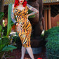 Woman in a tiger-patterned dress standing in front of a large statue with plants around.