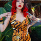 Woman in a tiger-striped dress with red hair and tattoos outdoors