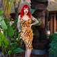 Woman in a tiger print dress standing next to a tiki statue in a tropical setting