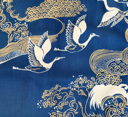 Decorative fabric with gold and white crane patterns on a blue background