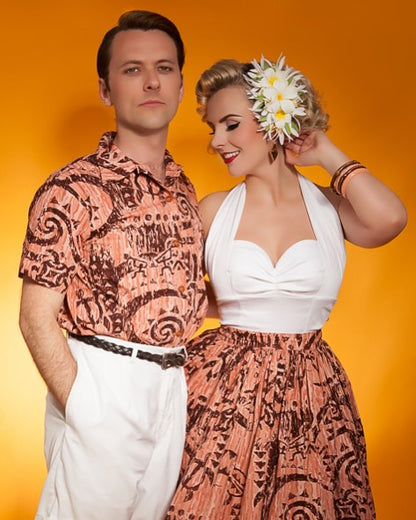 Two people in matching patterned outfits against an orange background