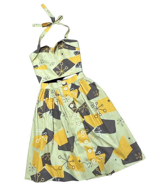 A 1950s style dress with atomic print consisting of a Dolly top and a buttoned skirt, primarily in yellow and gray tones.